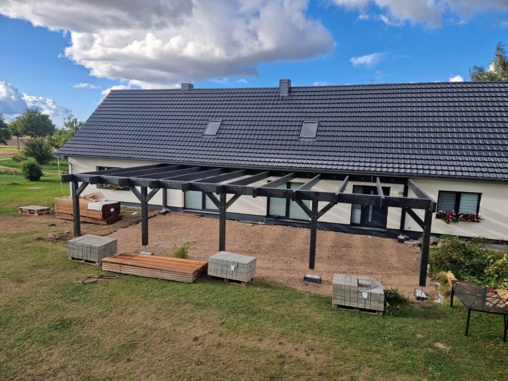 Terrasse mit Pergola im Aufbau. Die Pergola wurde zuerst errichtet, nun folgt der Aufbau der Bangkirai Terrasse durch Holzbau-Leistungen von Holzbau K. Jager
