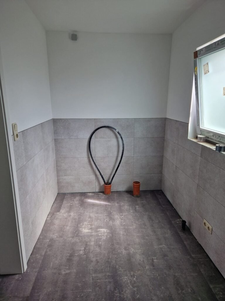 Badezimmer mit grauem Vinylboden und modernem Wandbelag in Fliesenoptik