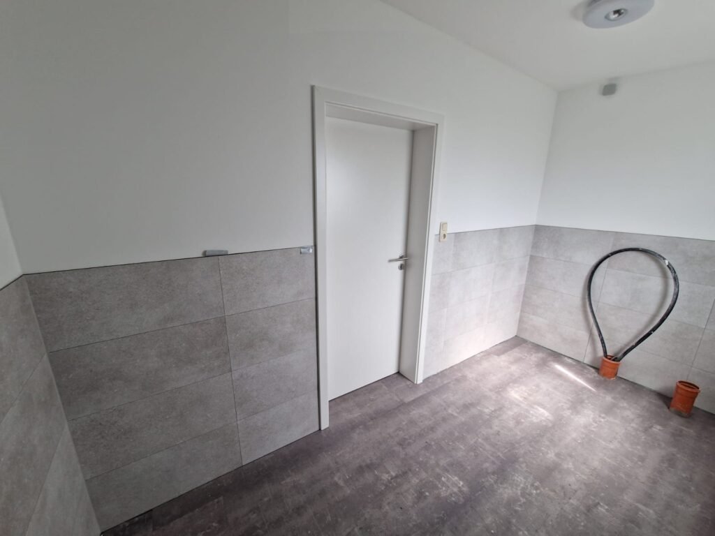 Badezimmer mit weißer Innentür und grauem Wandbelag